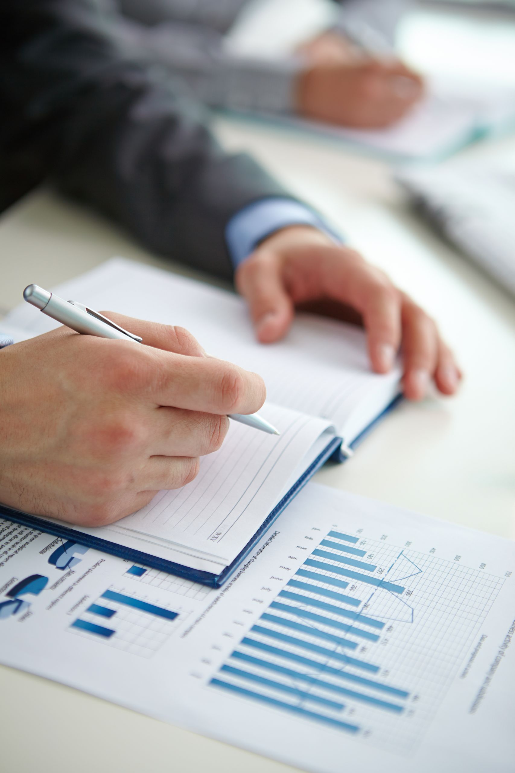 Businessman hand with pen over open notebook making report